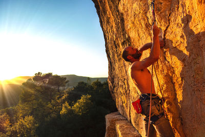 Man standing on rock against sky