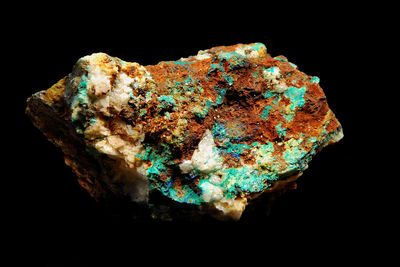 Close-up of rusty metal on rock against black background