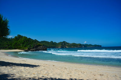 Scenic view of beach against clear blue sky