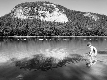 Side view of boy playing in lake against mountain