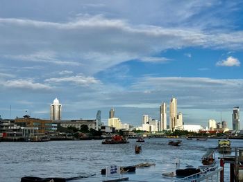 Buildings at waterfront against cloudy sky