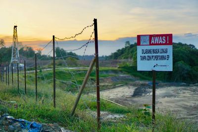 Information sign on field against sky