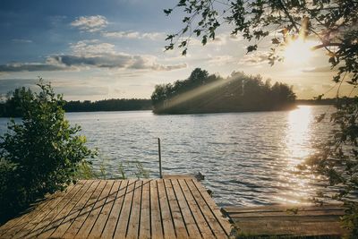 Pier over lake against sky during sunset