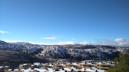 Houses by mountains against blue sky