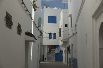 Rear view of people standing in alley amidst buildings