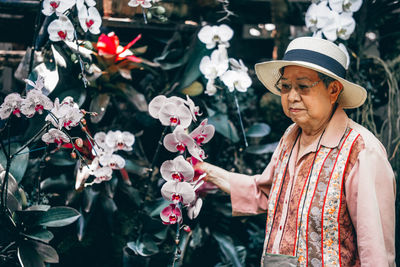 Portrait of woman standing by flowering plants