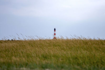 Lighthouse on field against sky