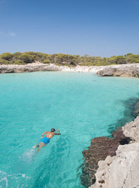 Man swimming in sea against blue sky