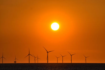 Silhouette wind turbine against sky during sunset