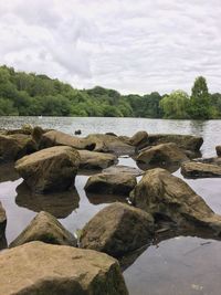 Rocks by river against sky