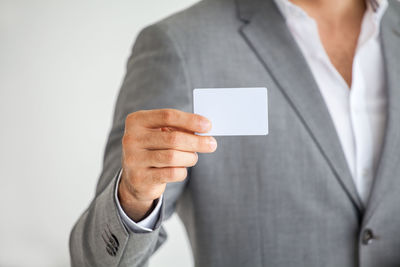 Midsection of man holding smart phone against white background
