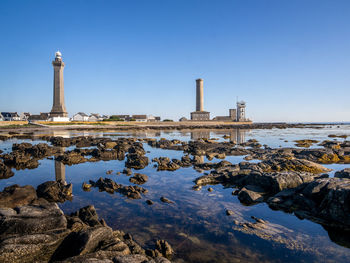 Lighthouse by sea against clear sky