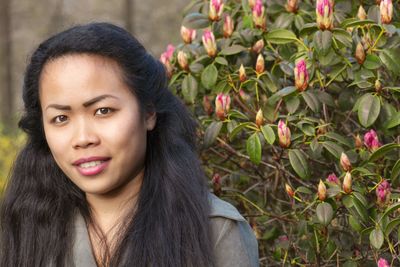 Portrait of beautiful young woman by pink flowering plants