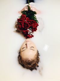 Beautiful woman holding bouquet in bathtub