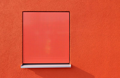 Close-up of closed red wall with a window