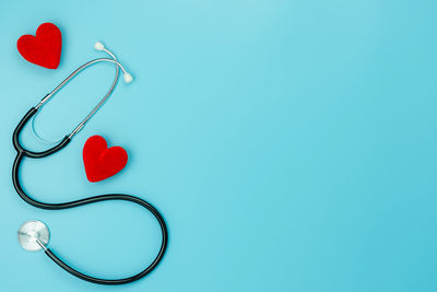 Directly above shot of heart shape by stethoscope against blue background