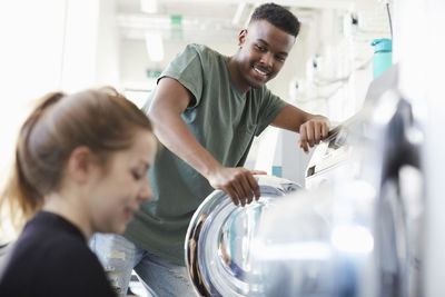 Young man looking at female university friend while doing laundry