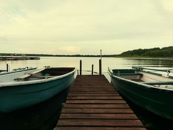 Boats moored at shore against sky during sunset