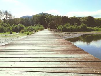 Boardwalk by lake against sky