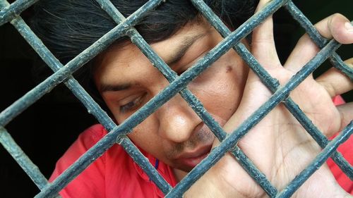 Portrait of man holding chainlink fence