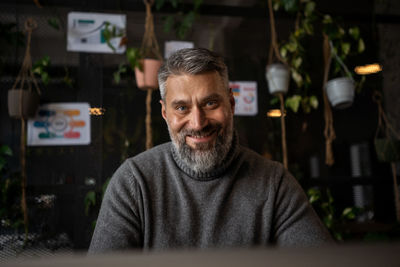 A man with facial hair is happily sitting at a desk in front of a computer