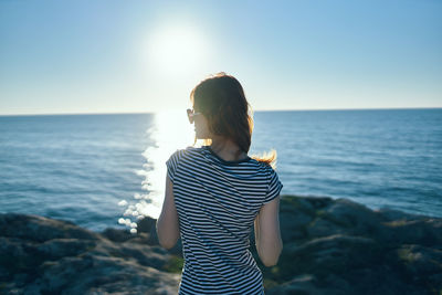 Young woman looking at sea against sky