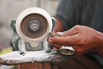 Midsection of man polishing ring in workshop