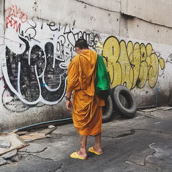 Man standing by graffiti on wall