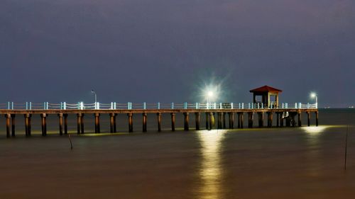 Pier over sea against sky at night