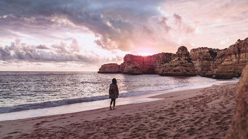 Full length of man on beach against sky during sunset