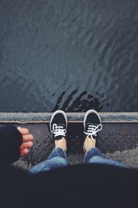 Low section of man standing on pier over lake