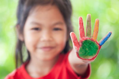 Close-up portrait of girl showing colorful paint on hand