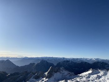 Scenic view of snowcapped mountains against blue sky