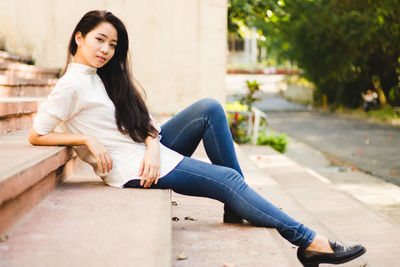 Portrait of young woman sitting on wall