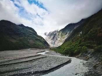 Scenic view of mountain road by river against sky