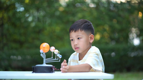 Close-up of cute boy playing with model on table in park