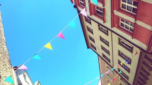 Low angle view of flags against clear blue sky