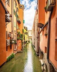 Canal amidst buildings in city against sky