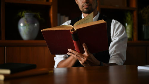 Midsection of man reading book