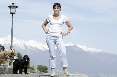 Portrait of woman with dog standing on mountain against sky