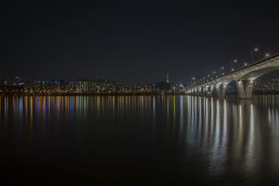 Illuminated bridge over river at night