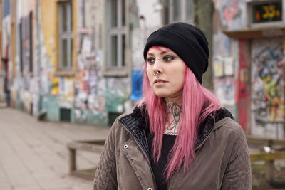 Young woman with pink hair standing on street