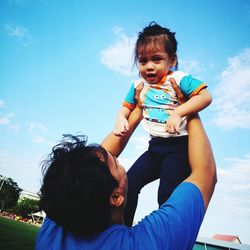 Father playing with daughter against sky