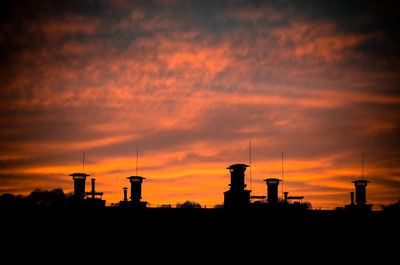 Silhouette of factory against sky during sunset