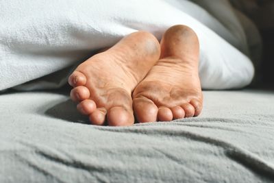 Low section of man relaxing on bed