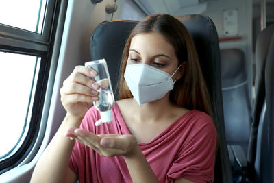 Woman using hand sanitizer in train