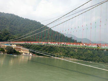 View of suspension bridge against cloudy sky