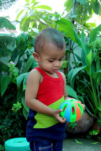 Child playing with ball, wearing colorful vest, portrait of asian baby boy play in home garden