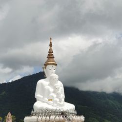 Low angle view of statue by building against sky