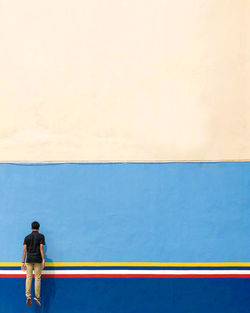 Rear view of man jumping against wall